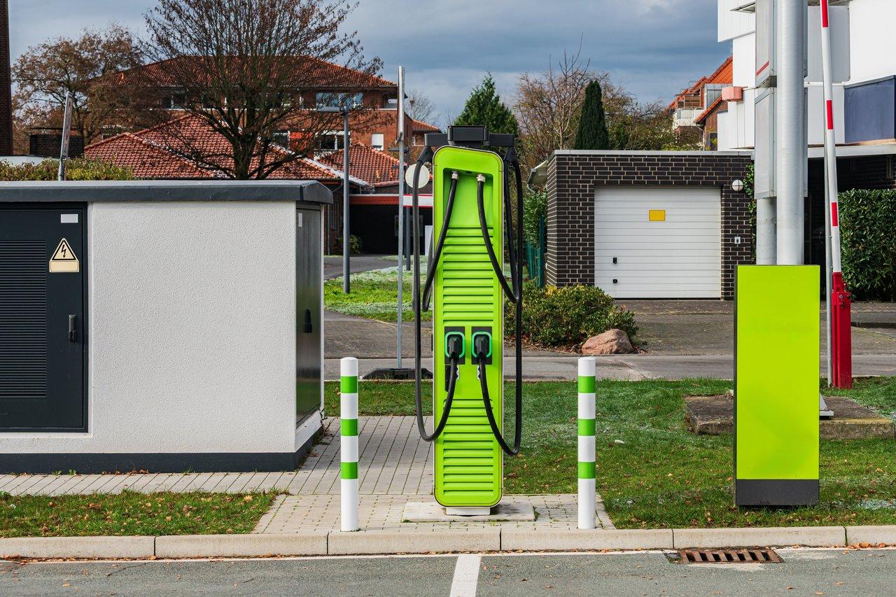 Station de recharge de véhicules électriques moderne dans un parking urbain périurbain équipé de bornes murales et totems.
