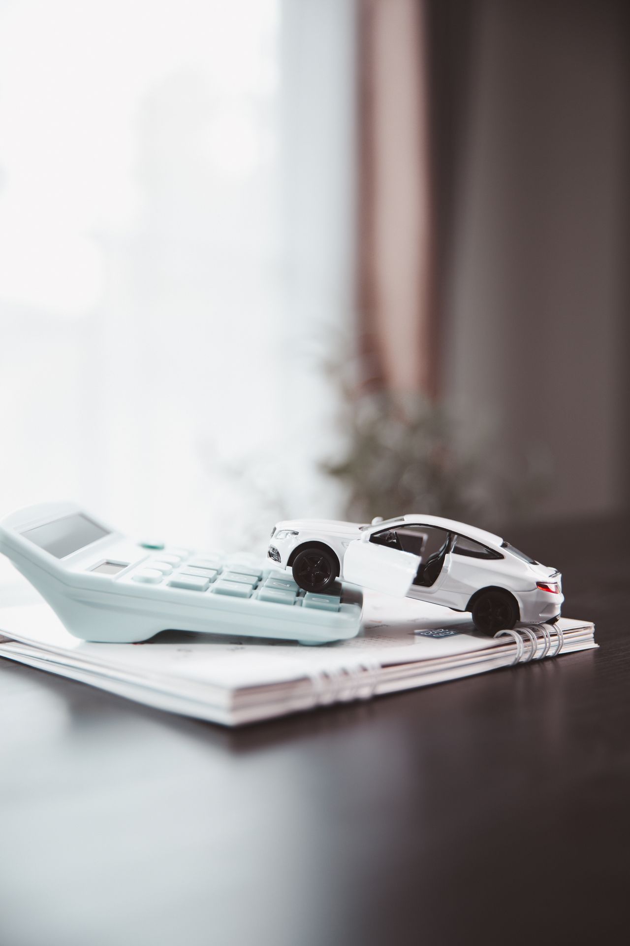Voiture miniature blanche posée sur une calculatrice et un carnet